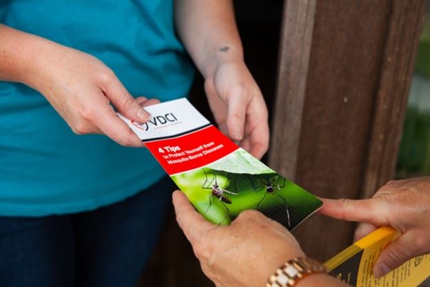 Person Handing Another Person a VDCI Pamphlet (JPG)